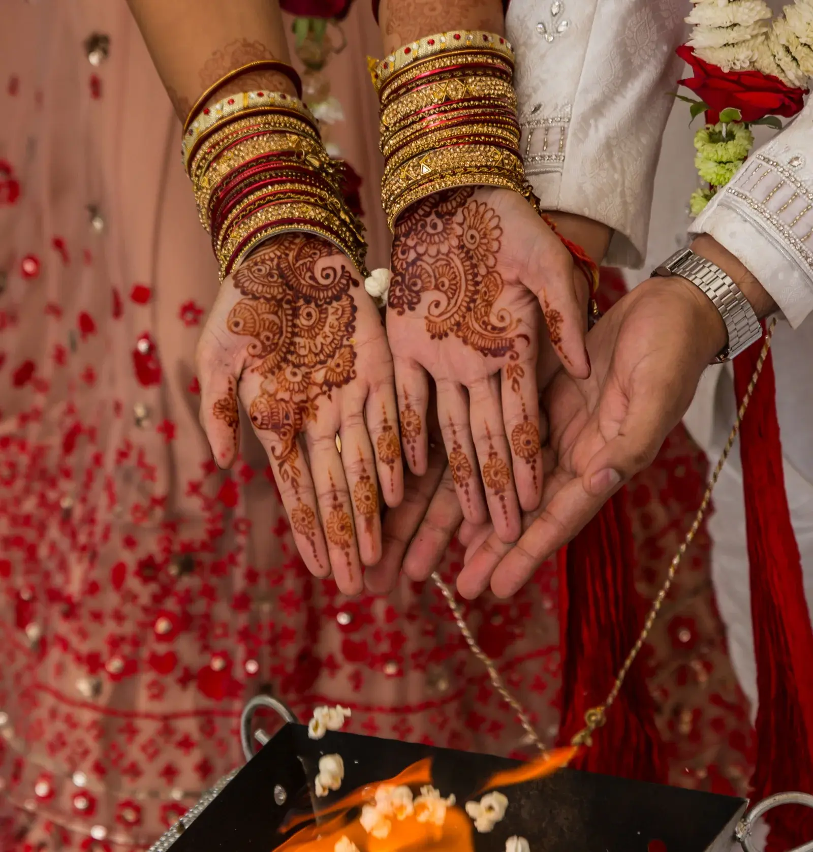 Bride and groom displaying intricate mehndi on palms during Hindu wedding ceremony with fire ritual